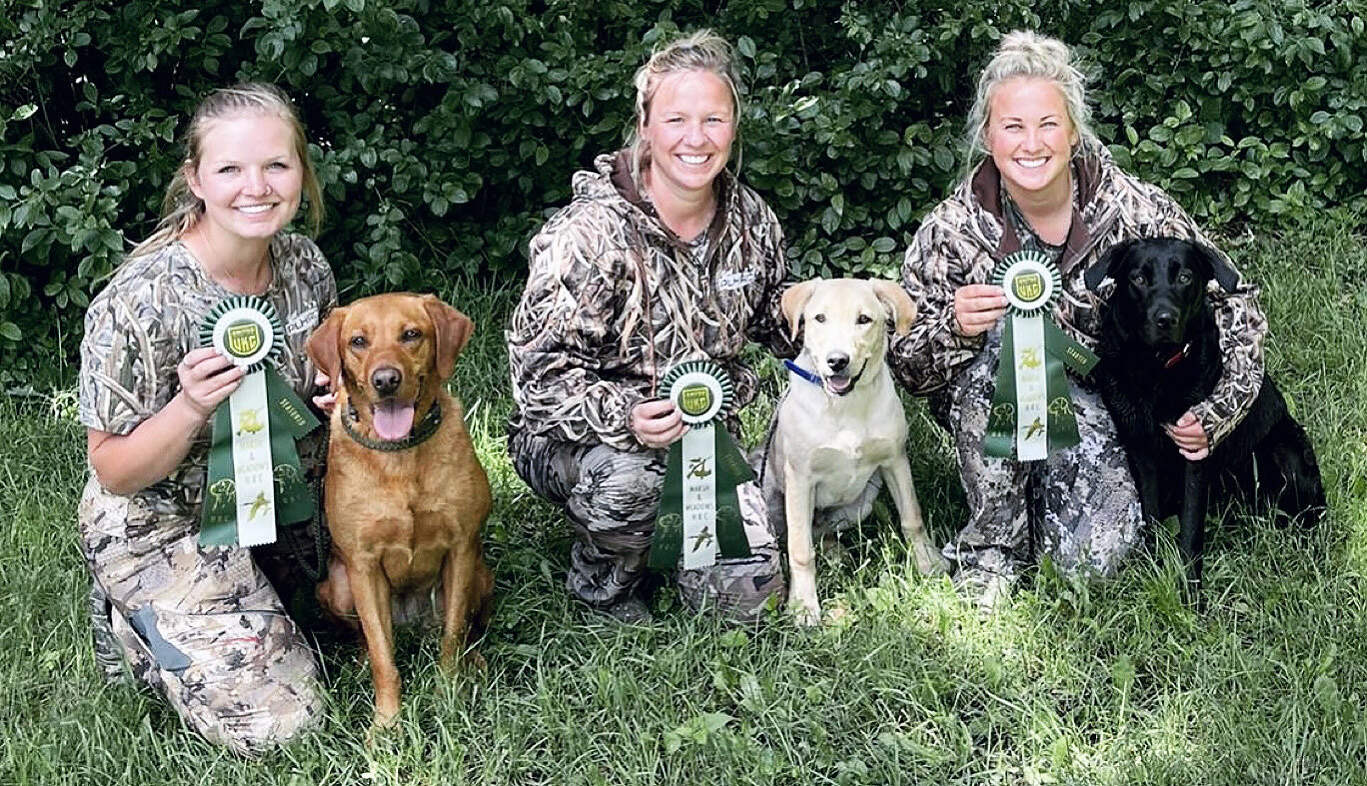 Three women and their dogs showing off award ribbons